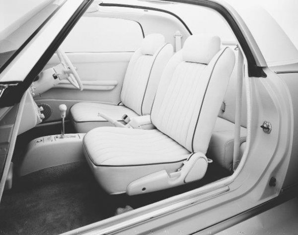パイピングの入ったフィガロオリジナルの本革シート。フロントシートのヘッドレスト下部、リアシート両サイドエッジ部分には革同士の摩擦音を防止するため合成皮革を採用している。後席は＋2のスペース