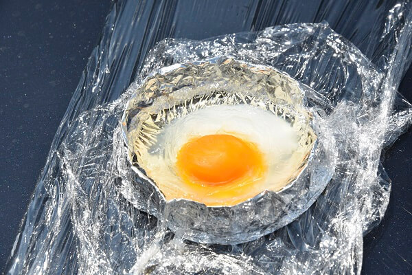 約80度のボンネットに2時間置いた卵。卵黄は65～70度前後で固まるため、卵白よりの顕著に違いがわかる。卵白も写真上部が固まっている。人間も同じたんぱく質なので、高温下に置かれれば命の危険がある