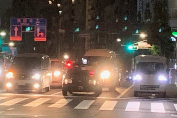 夜間の交差点、真ん中のタクシーはヘッドライトを消し、スモールランプを点けている