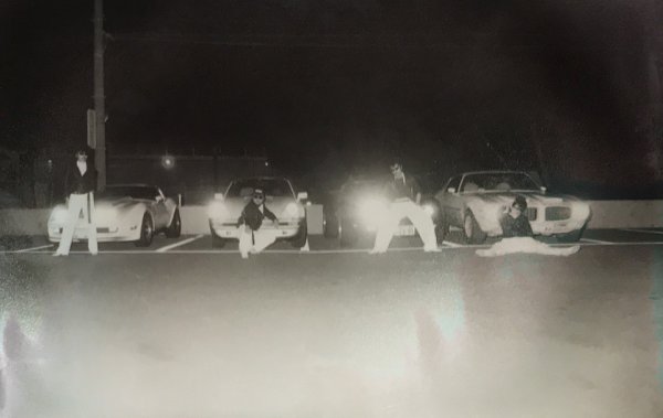愛車の前でポーズを取るメンバーたち。左からTAKU、嵐、翔、Johnny。クルマは左からシボレー・コルベット・スティングレイ、ポルシェ930ターボ、シボレー・コルベット・スティングレイ、ポンティアック・ファイアーバード・フォーミュラ400