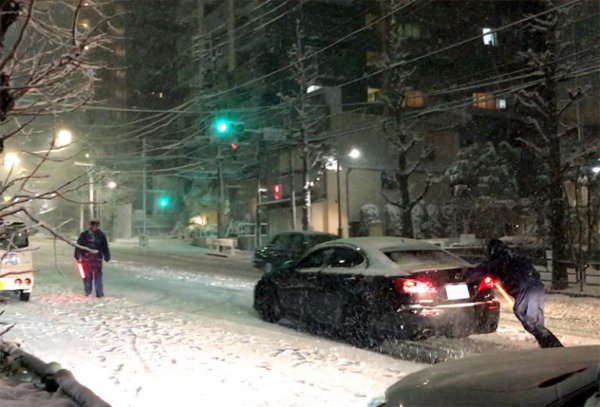 2018年1月22日、都心部で4年ぶりに20cmを超える大雪が降ったが、その時にサマータイヤを履いたまま走り、坂道で道路を塞ぐクルマが目立った。写真はサマータイヤを履いたクルマを警察官が押している様子