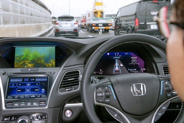 高速道路上で「レベル3」体験中。Honda SENSING Eliteハンズを搭載した新型レジェンドであれば、一定の条件を満たせば走行中にハンズオフ（ステアリングから手を離す）だけでなく、アイズオフ（周囲を注視することなく車載モニターでDVDを鑑賞するなど）も可能になる