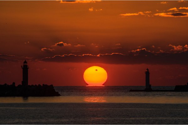 留萌港の灯台の間に沈む「だるま夕陽」