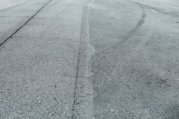 路面洗浄後の境目を見ればその差は一目瞭然。洗浄前の写真右にあるタイヤ痕も写真左の境目でキレイに消えている