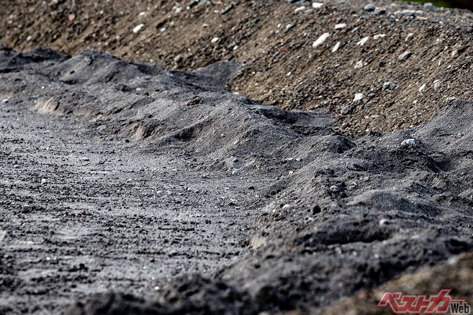 写真左側手前が降灰している走行箇所。右手上方の普通の土部分に比べて、全体的に目が細かい