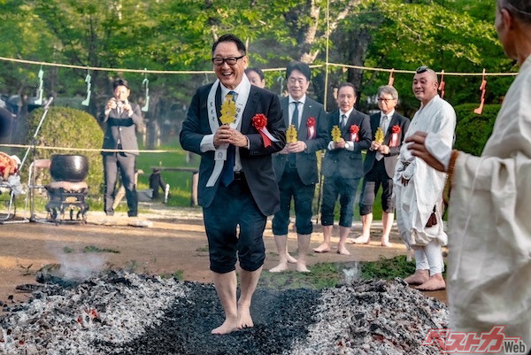 焚き上げられた護摩木の残り火の上を歩き、厄除けや無病息災を祈願する火渉り式に参加する豊田章男会長。熱くても笑顔を絶やさないのはさすがです