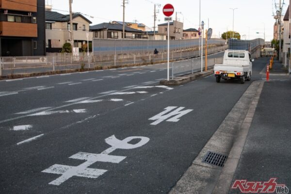 一般道での側道から本線へ合流する場合、道路には止まれの表示がある。クルマは本線に向かって（左）走るが、写真の軽トラは逆走している。当然違反（写真AC）