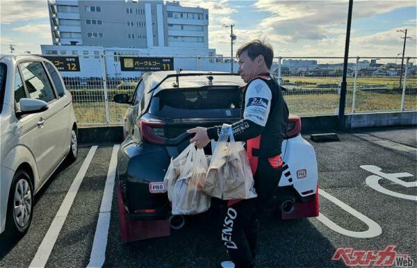 チームのために買い込んだグラコロ20個をクルマに積み込む小林可夢偉選手