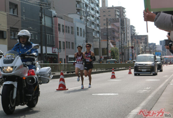 10区で3位争いを繰り広げる早稲田大学と国学院大学の選手。熱いデッドヒートに感動! その後ろには大学関係者が乗るノア/ヴォクシーが走る