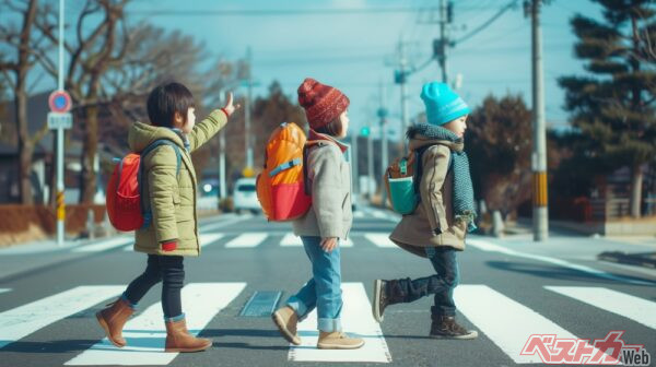 手を上げて歩道を渡る子供。時にお辞儀をする時もありほっこりするfumoto-lab@Adobe Stock