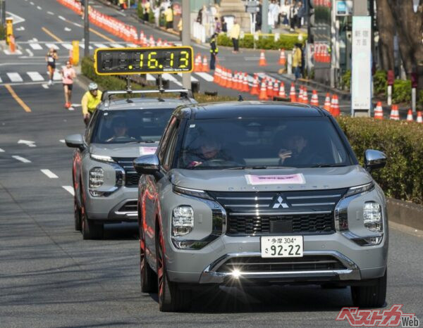 先導車とタイマー車、2台のアウトランダーPHEV。カッコいいぜ! 後方に先導する自転車と2人のランナーが見える