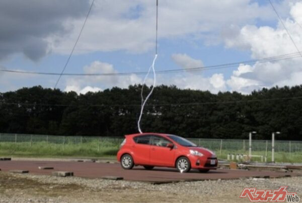 JAFが行った実験の様子。一般的な雷の電圧を模擬した1200万ボルトの衝撃電圧発生装置でクルマに気中放電したが、車内のマネキンには影響がなかった(JAF「落雷時、車や車内にいる人への影響は?(JAFユーザーテスト)」より)