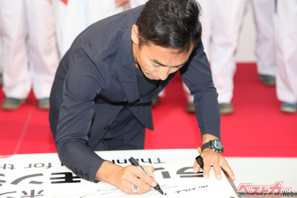 バナーにサインを書き込む佐藤琢磨氏。「No Attack、No Chance」は常に攻め続ける佐藤氏の代名詞となっている