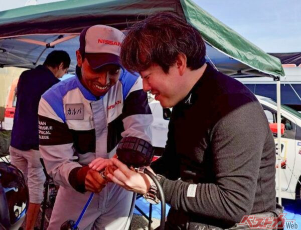 エアゲージの使い方をコ・ドライバーに教える日産京都自動車大学校の留学生。空気圧調整ができるようになったぞ!