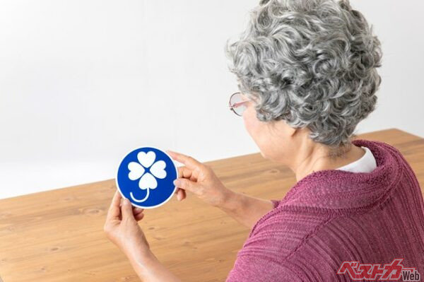 白のクローバーが特徴の身体障がい者標識。車いすマークとはちょっと違うぞ(buritora@Adobe Stock)