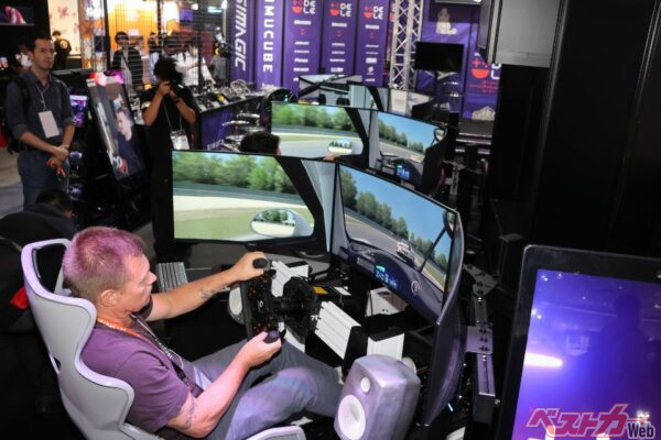 DELE(デーリー)ブースの「TRAK RACER」のドライブシュミレーターを試走するミカ・サロ選手