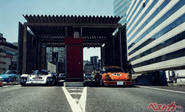 料金所越しにスタートダッシュを決めようとするポルシェ・シュパン 962Cロードカーコンバージョンと911ナロー