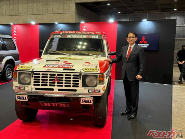 ダカール・ラリー優勝車の前で、笑顔で写真撮影に応じる三菱自動車の岸浦恵介新社長