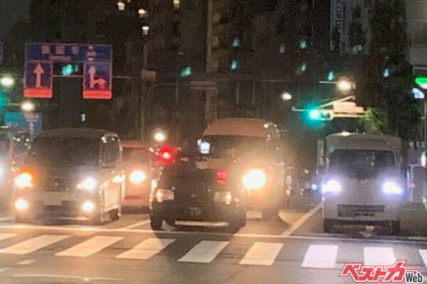 夜間の交差点でヘッドライトを消している中央のタクシー。こうしたシーンはよく見かける