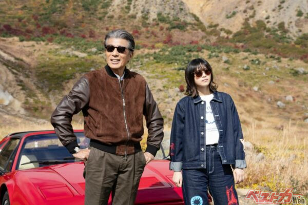 福島の磐梯吾妻スカイラインでフェラーリをバックに並ぶ南条と川奈。日本とは思えないような絶景の中をフェラーリが走るシーンは注目です。©2026「免許返納!?」製作委員会