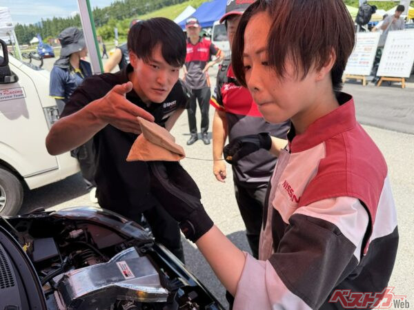 オイル量のチェックをする日産自動車大学校の学生さんと神奈川ダイハツからDGRに出向中の遠藤さん（日産横浜自動車大学校卒業生！）