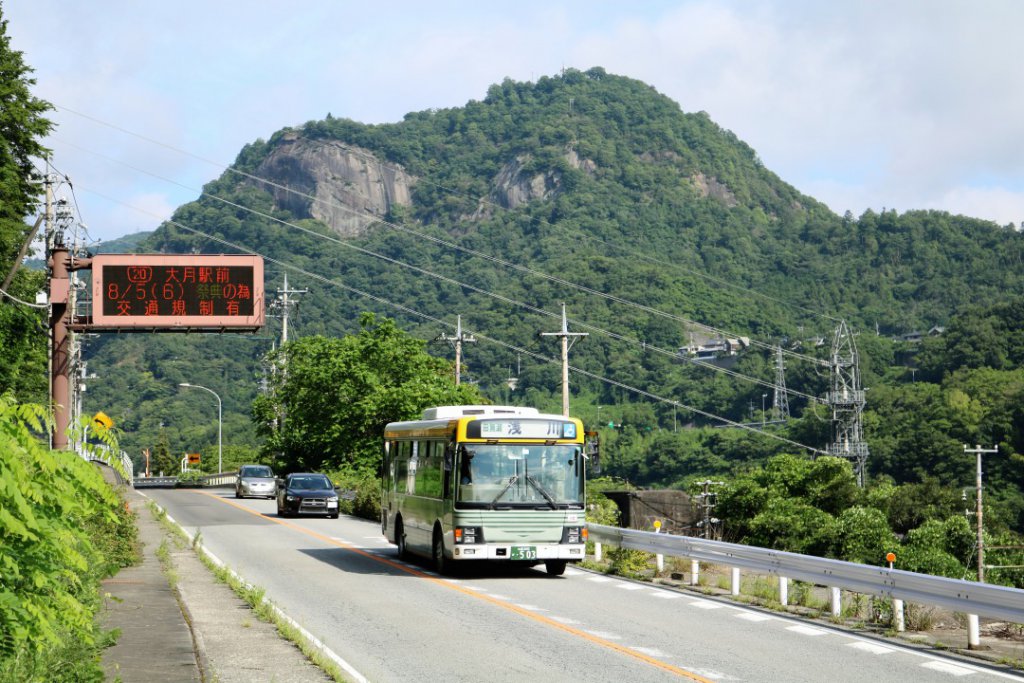 昔、赤鬼が住んでいたと言い伝えられる岩殿山を背後にして走る富士急山梨バス