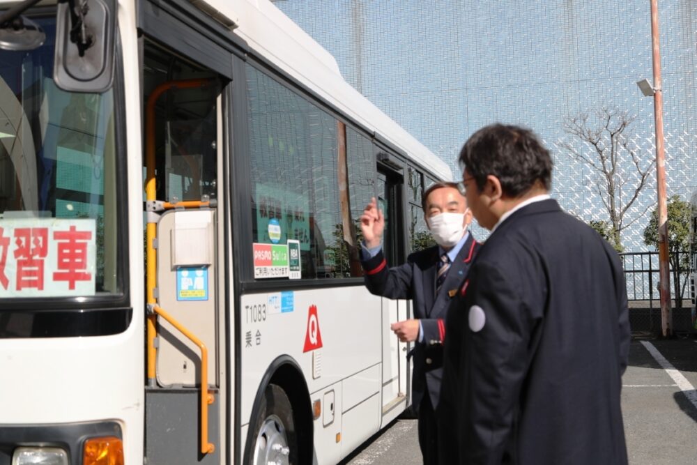 営業所内で教官から車両点検の指導を受ける