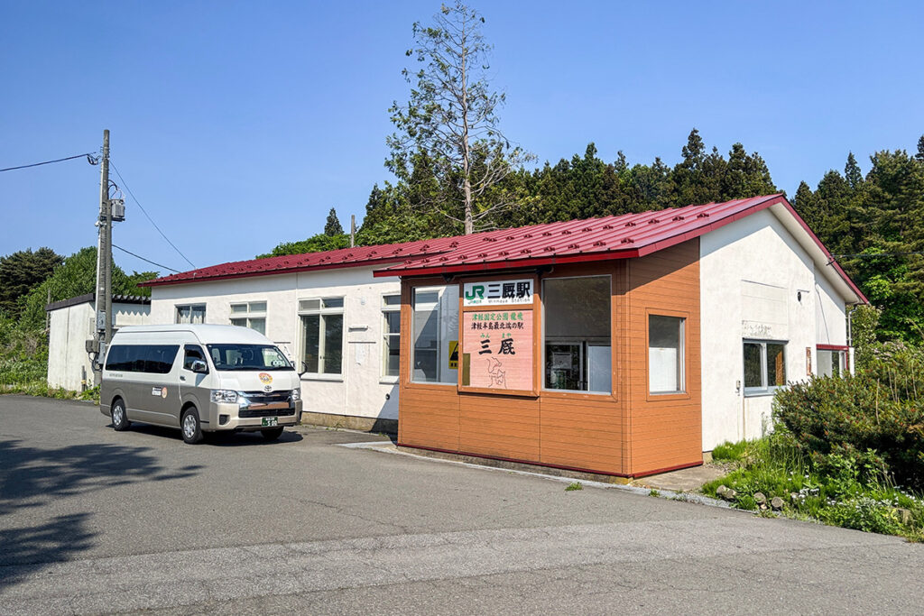 2025年5月現在の三厩駅。駅前にトヨタ・ハイエースを使用した「わんタク定時便」が停車中