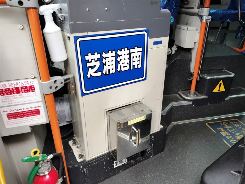 誤乗防止の路線名ボードと金庫を持ってバスに向かう