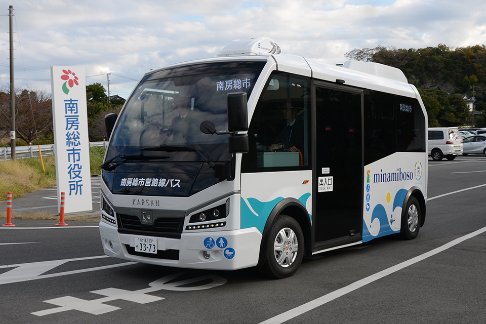 南房総市役所から発進するe-JEST。緩い上り坂をスル〜っと発車。車両の左側面(扉側)は海をモチーフにしたデザインが施されている