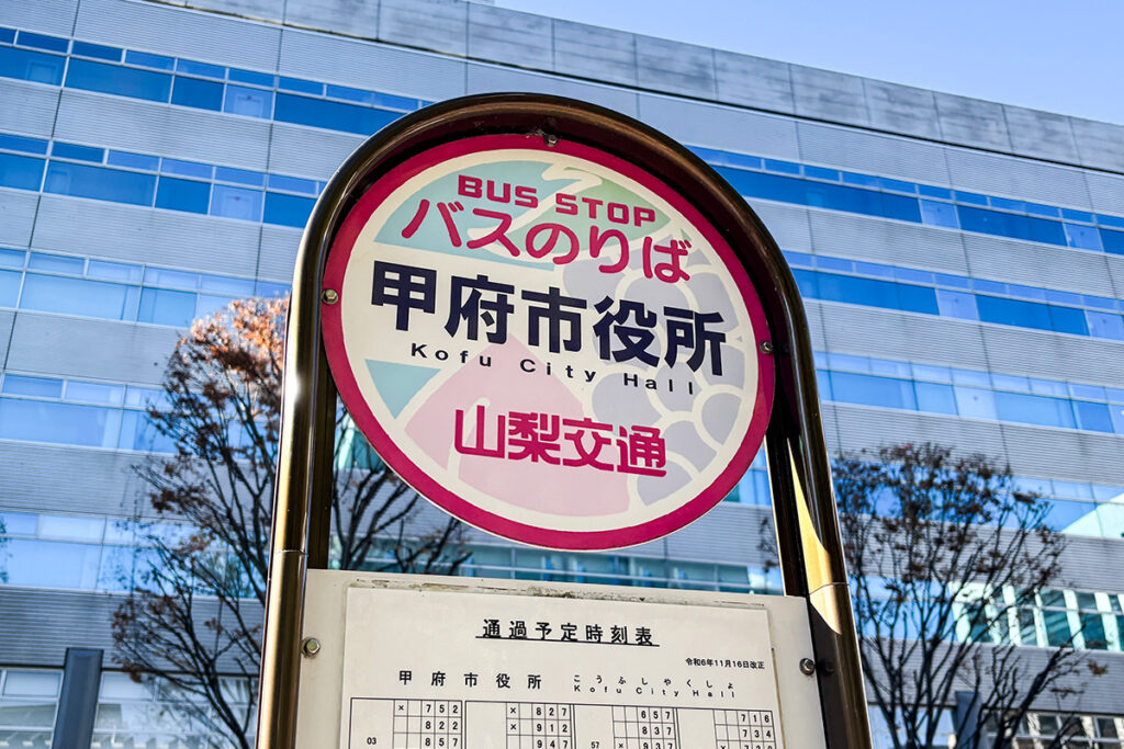 甲府市役所バス停。よくよく眺めると標識に図柄が入っている