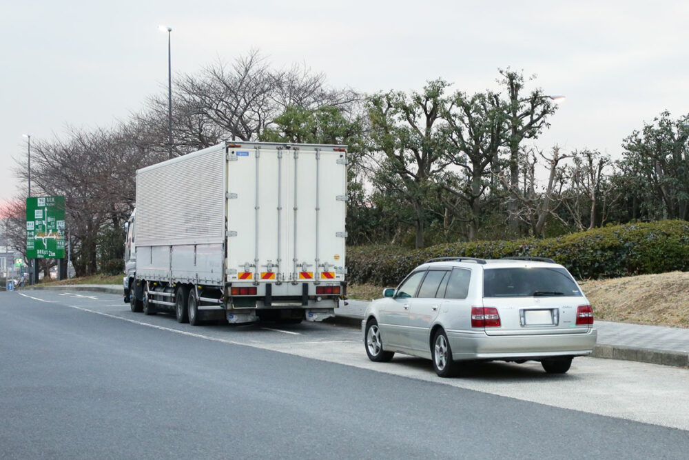 サービスエリアのトレーラマスに停める単車のトラックと乗用車