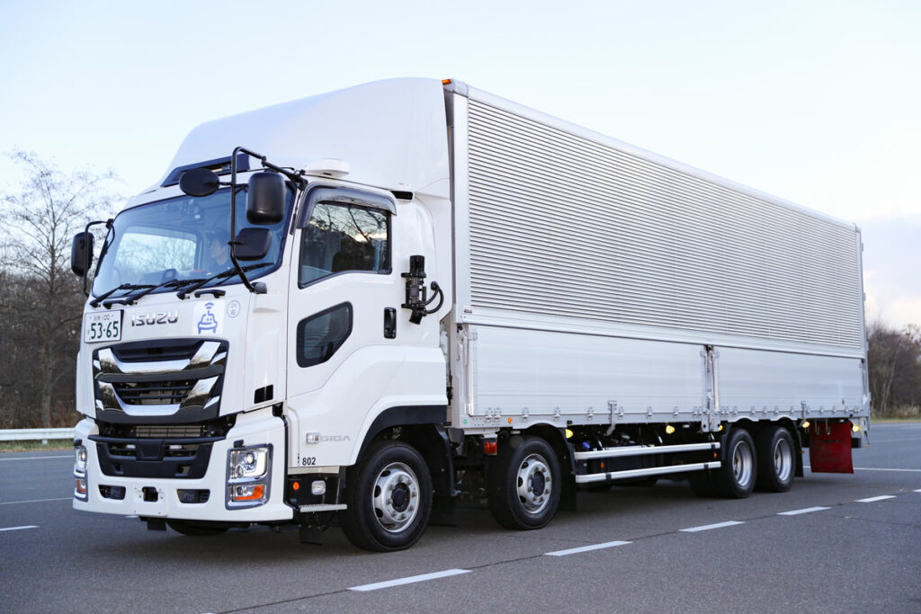 走行デモ＆試乗に用いられたギガCYJ系ベースの自動運転トラック（第一世代）。システムはLiDAR6台、ミリ波レーダー6台、GNSS1台、IMU1台、セルラーアンテナ1基という構成。自動運転作動中ランプと停止表示灯も備える