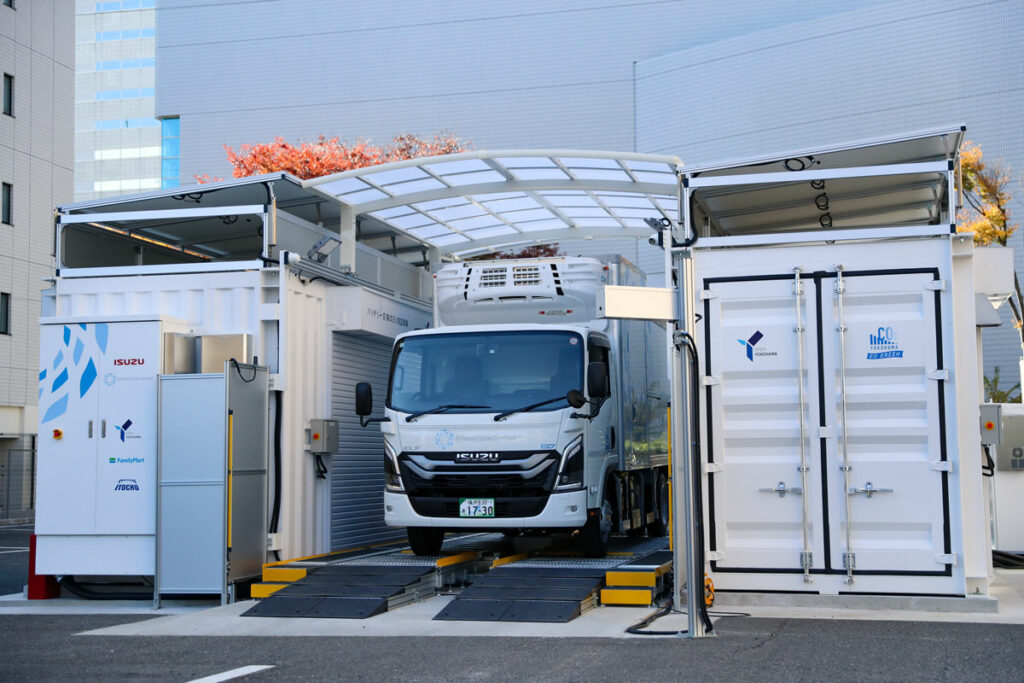 バッテリー交換ステーション。車両停止位置補正装置の左右に交換装置＆バッテリーを収める20フィートコンテナを配すレイアウトなど基本構成は藤沢工場のステーションと同じだ