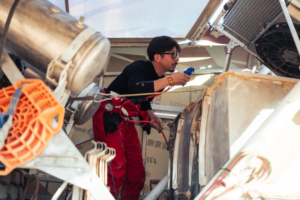 翌日の競技に備え車両点検を行なう乗員メカニックの望月裕司