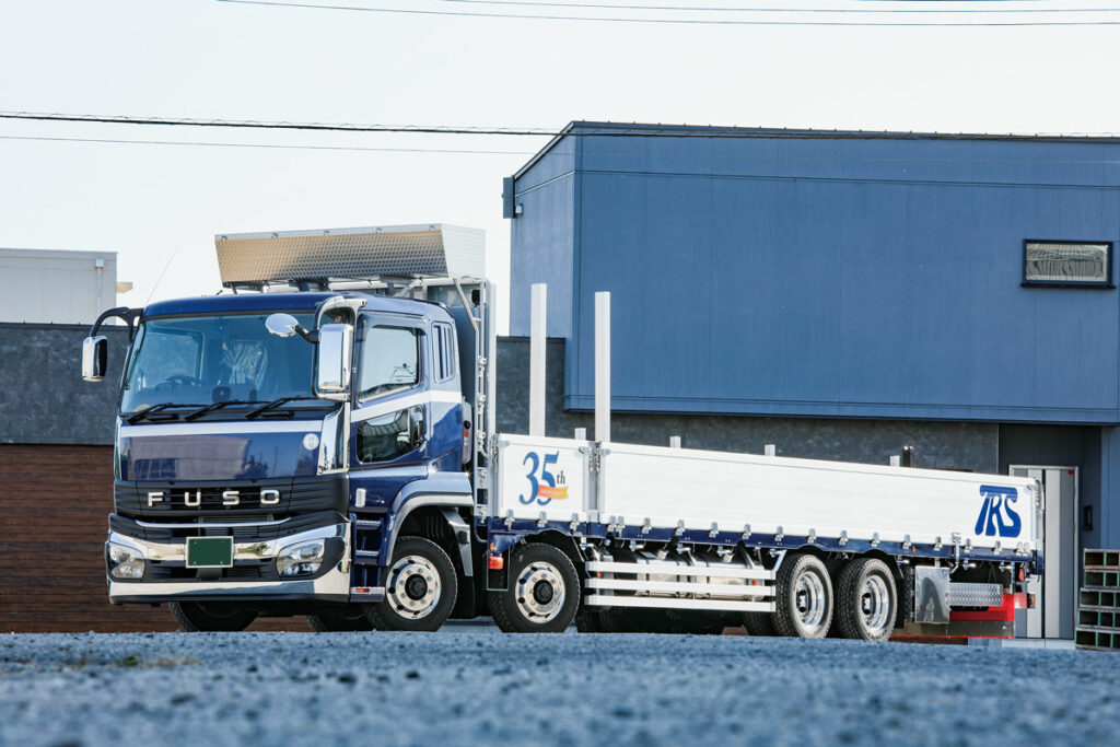 丸安が製作した大型平ボディ。ベース車両は三菱ふそうスーパーグレートFS系GVW25トン級4軸低床8×4リアエアサスシャシーの標準ルーフ仕様だ