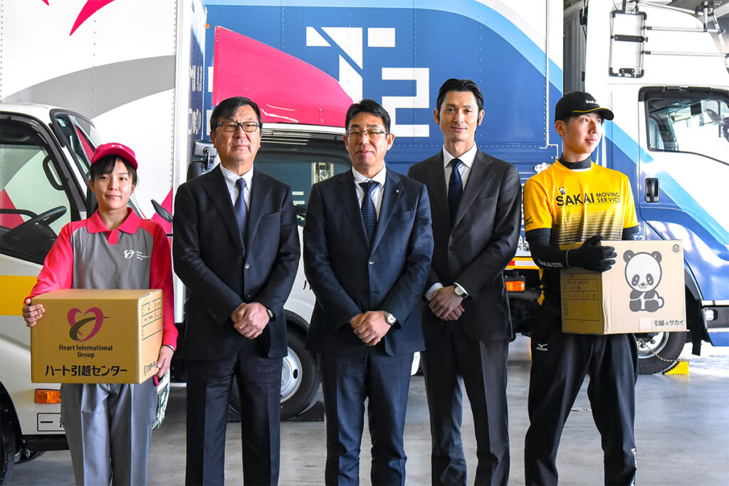 中央3人の左からハート引越センターの太田至計社長、サカイ引越センターの山野幹夫専務、T2の熊部雅友CEO