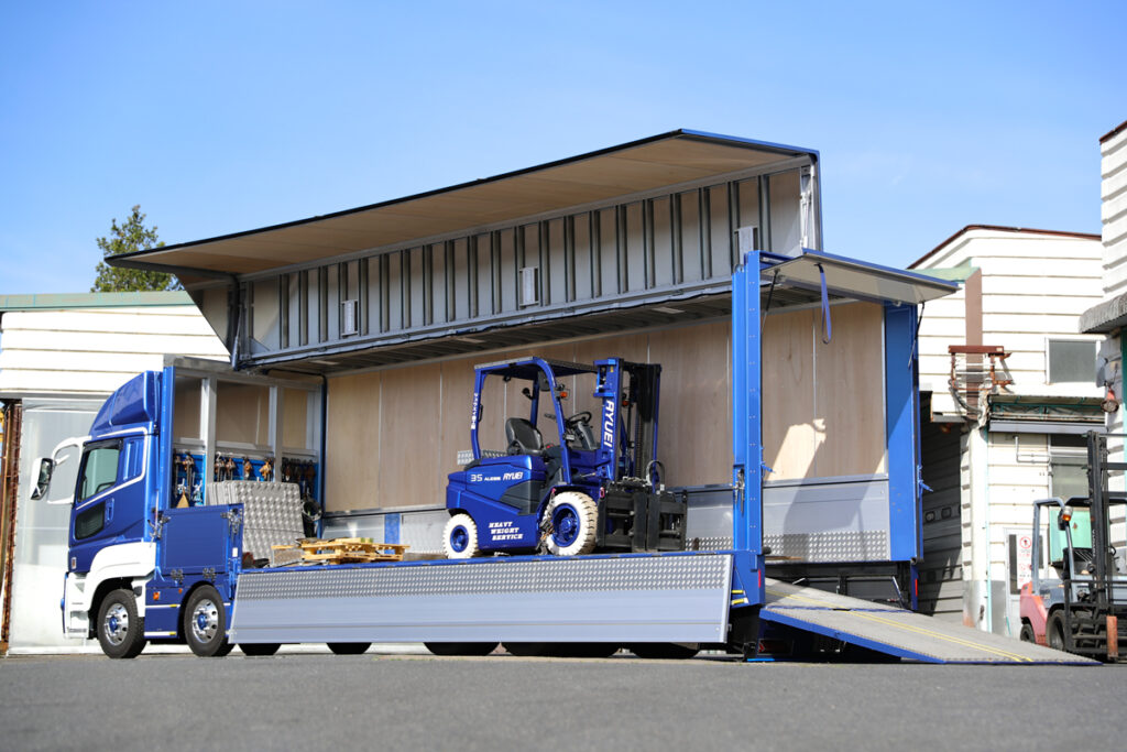 荷台フルオープン状態。フォークリフトの自走積み降ろしに不可欠なテールオートに、密閉性の高いウイングボディを合体させた唯一無二のボディだ