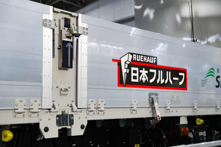 ロック装置の解除も自動化！　日本フルハーフとシンフォニアテクノロジーが共同開発中の「電動式アオリ開閉補助装置」のさらなる進化に驚き！